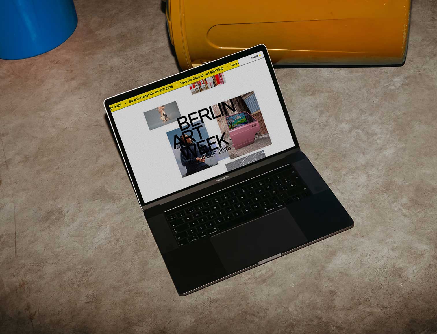 Laptop mit offenem Bildschirm, der eine Website zur Berlin Art Week auf grauem Boden zeigt.