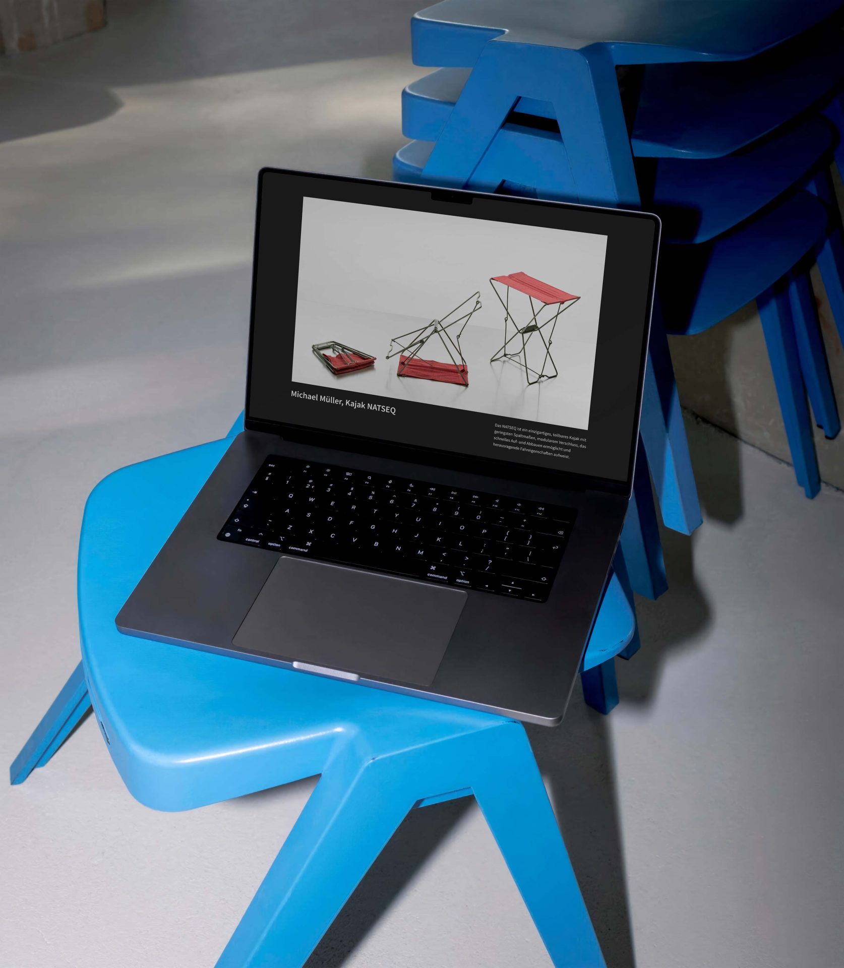 Laptop auf blauem Stuhl, zeigt ein Designprojekt mit Tischmodellen auf dem Bildschirm.