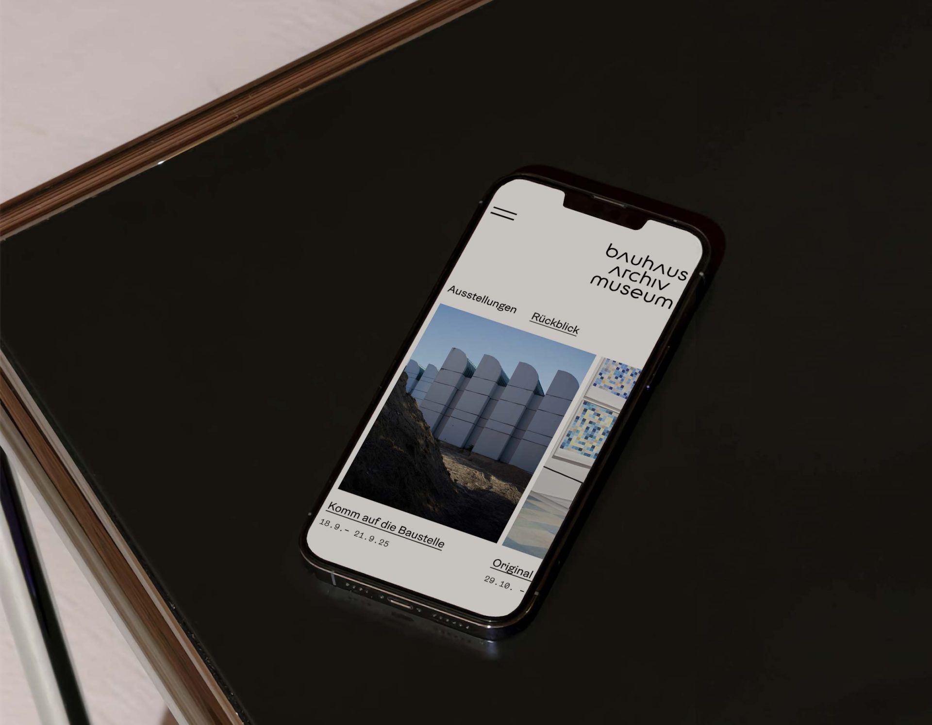 Smartphone liegt auf einer dunklen Oberfläche mit einer offenen Museumswebsite.